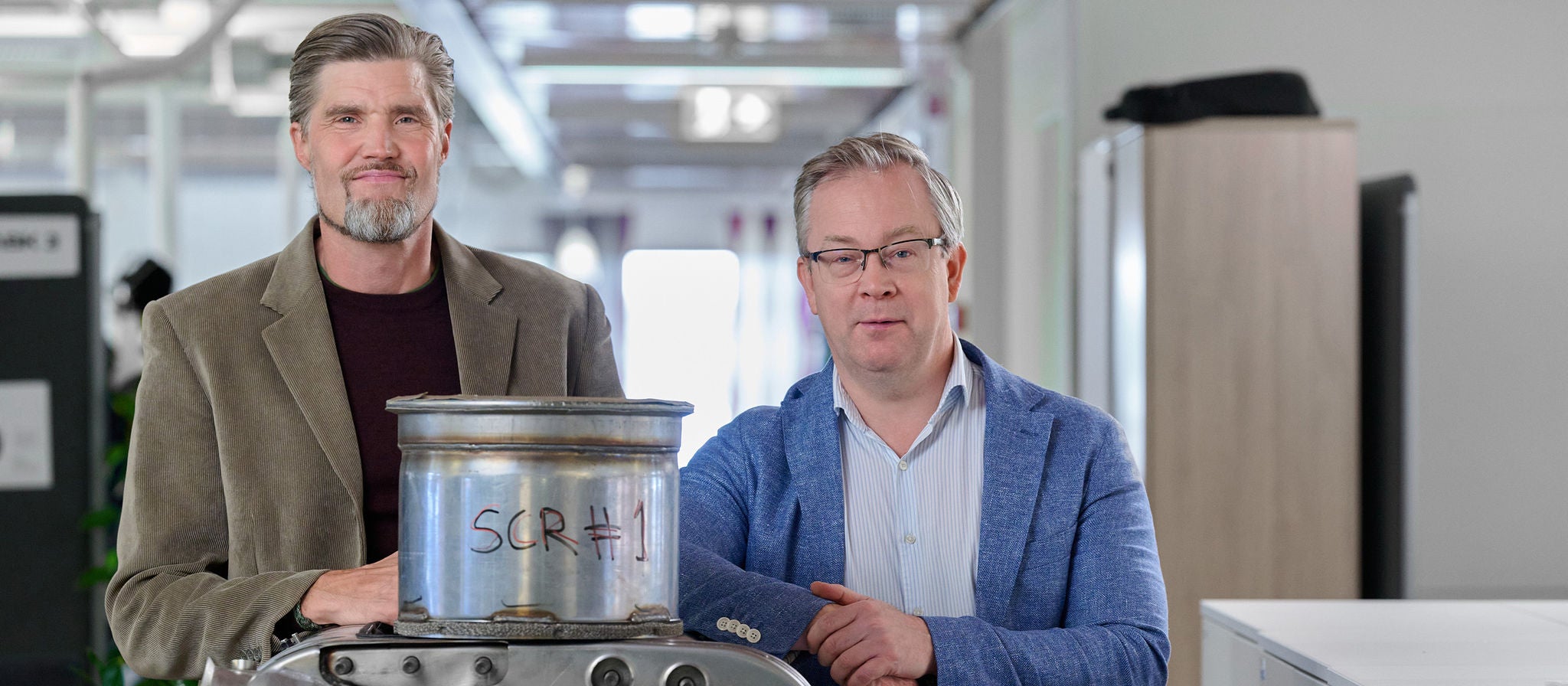 Henrik Birgersson and Magnus Nilsson, standing infront of their invention: the Twin SCR system. An invention which makes more efficient use of the exhaust temperature and cleans harmful emissions from exhaust gases in two stages.