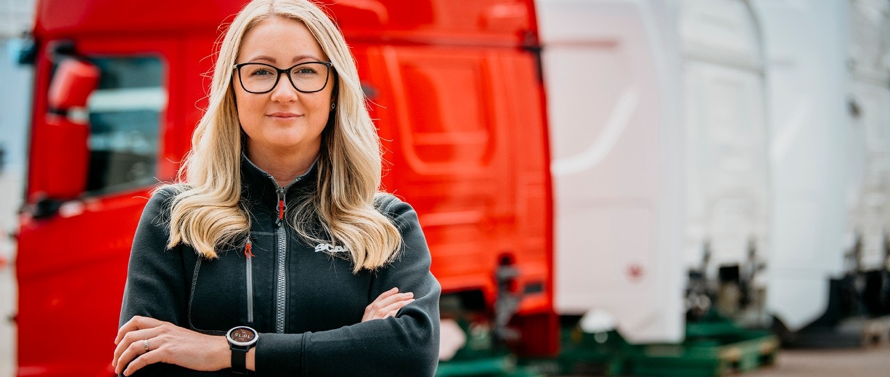 Porträttbild på medarbetare som står framför en röd hytt