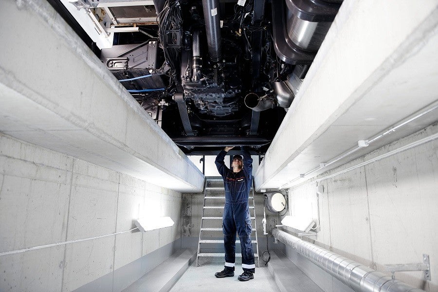 Technician working under a truck in workshop