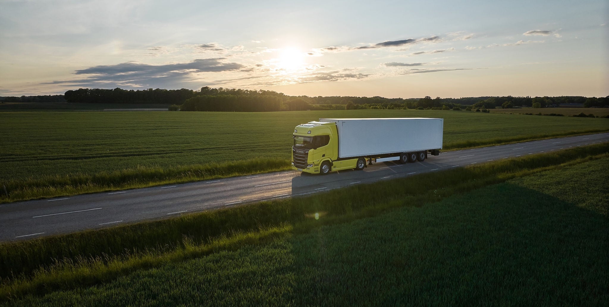 Scania truck driving by green fileds