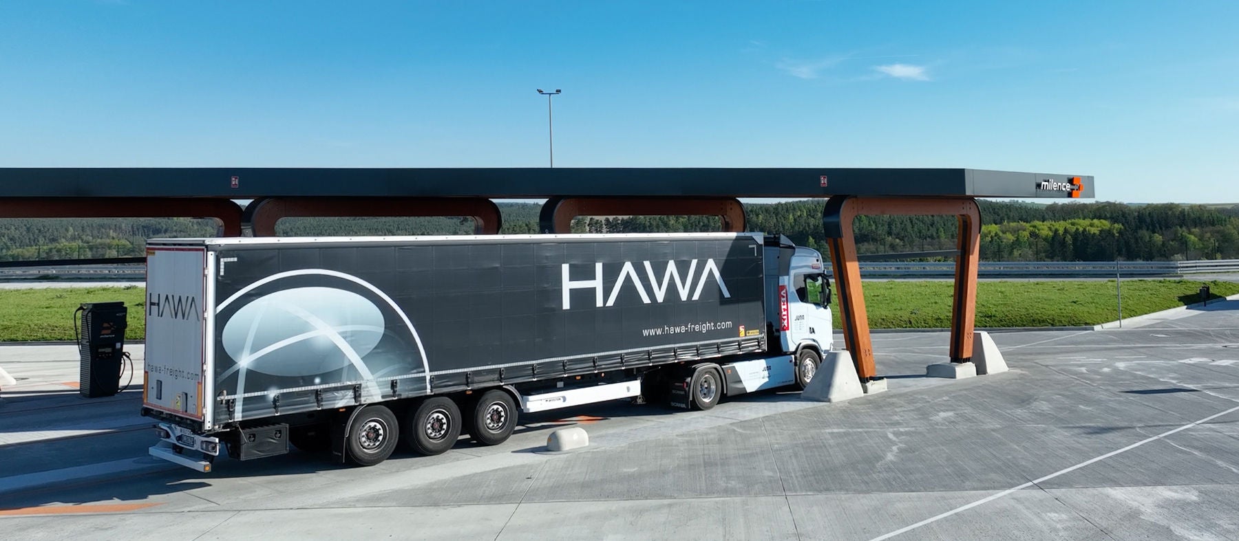 A Scania battery-electric truck operating a VELUX logistics route charges at a public charging station.