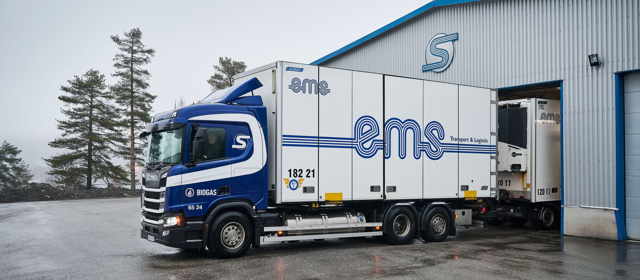A blue Scania biogas truck parked outside EMS Transport & Logistik's terminal in Örnsköldsvik, Sweden.