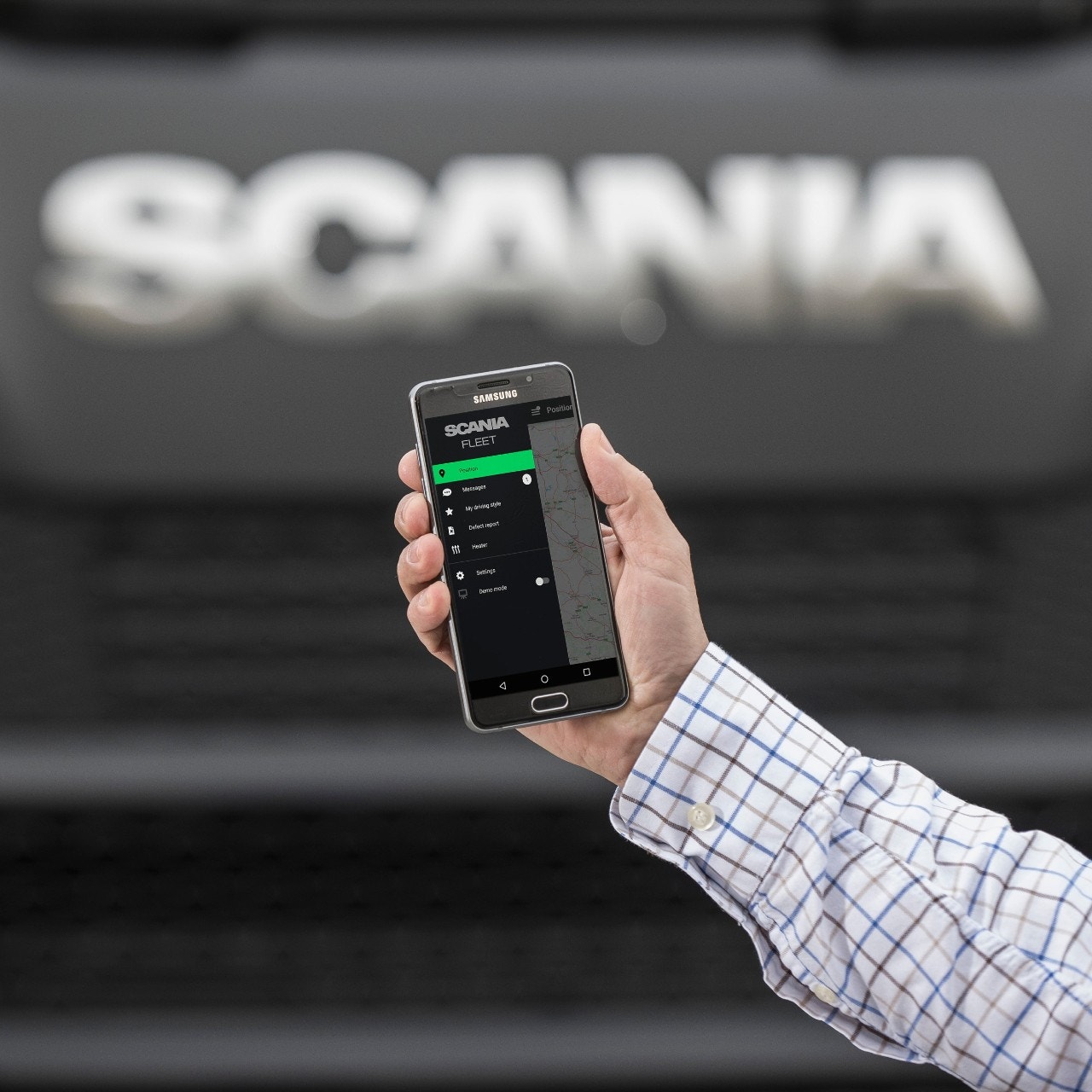 Håller i en smartphone framför en Scania