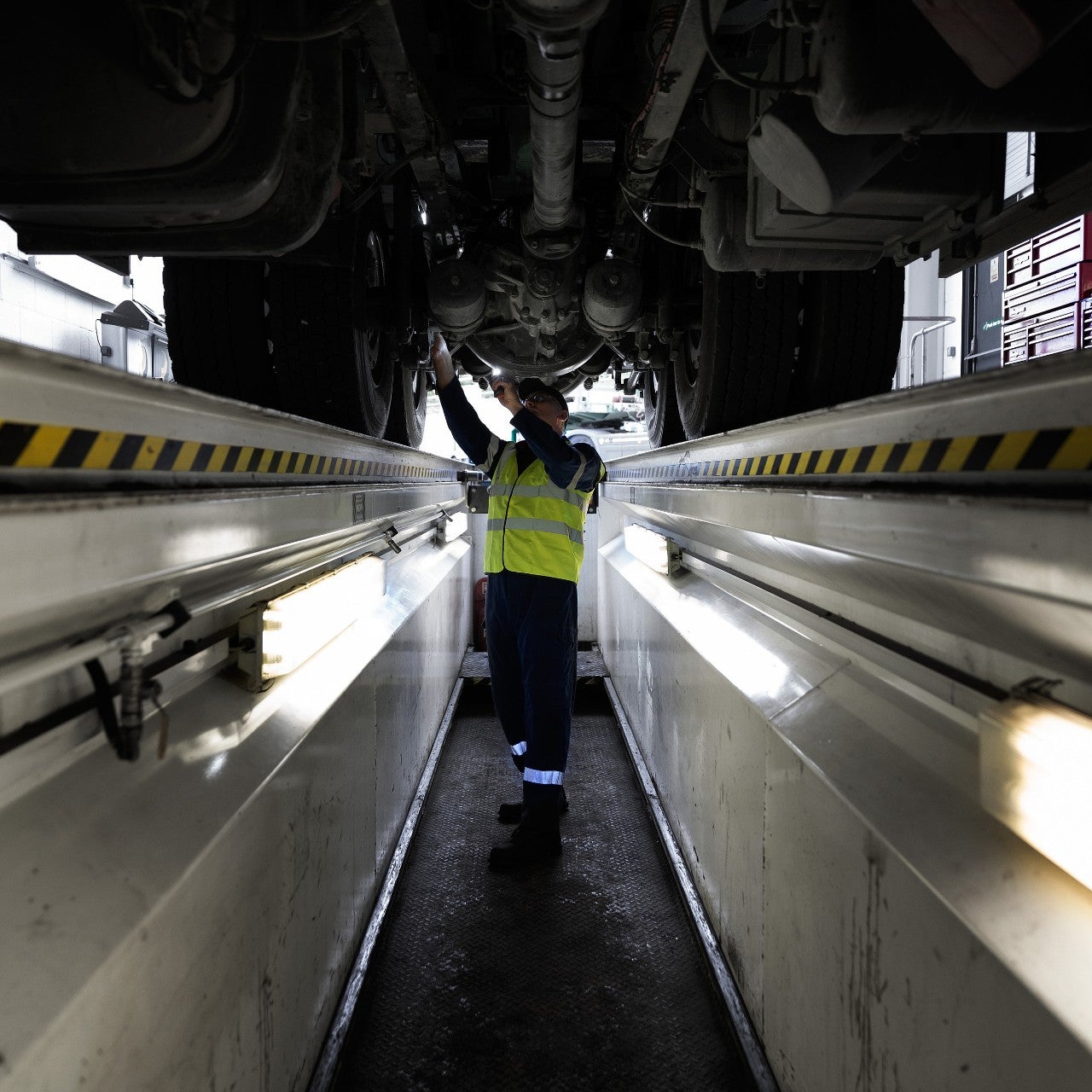 Werkstattmitarbeiter repariert Lkw in der Grube