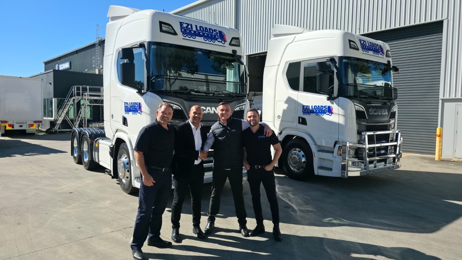 our men posing in front of two white Scania Ezi Loads trucks.