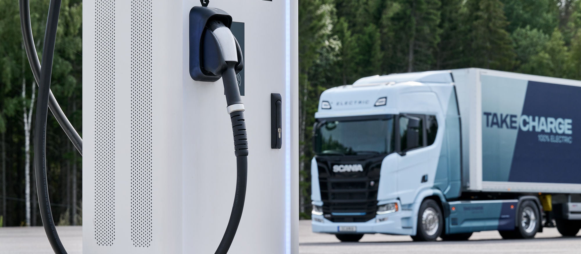 Ciężarowy pojazd elektryczny Scania przy stacji ładowania
