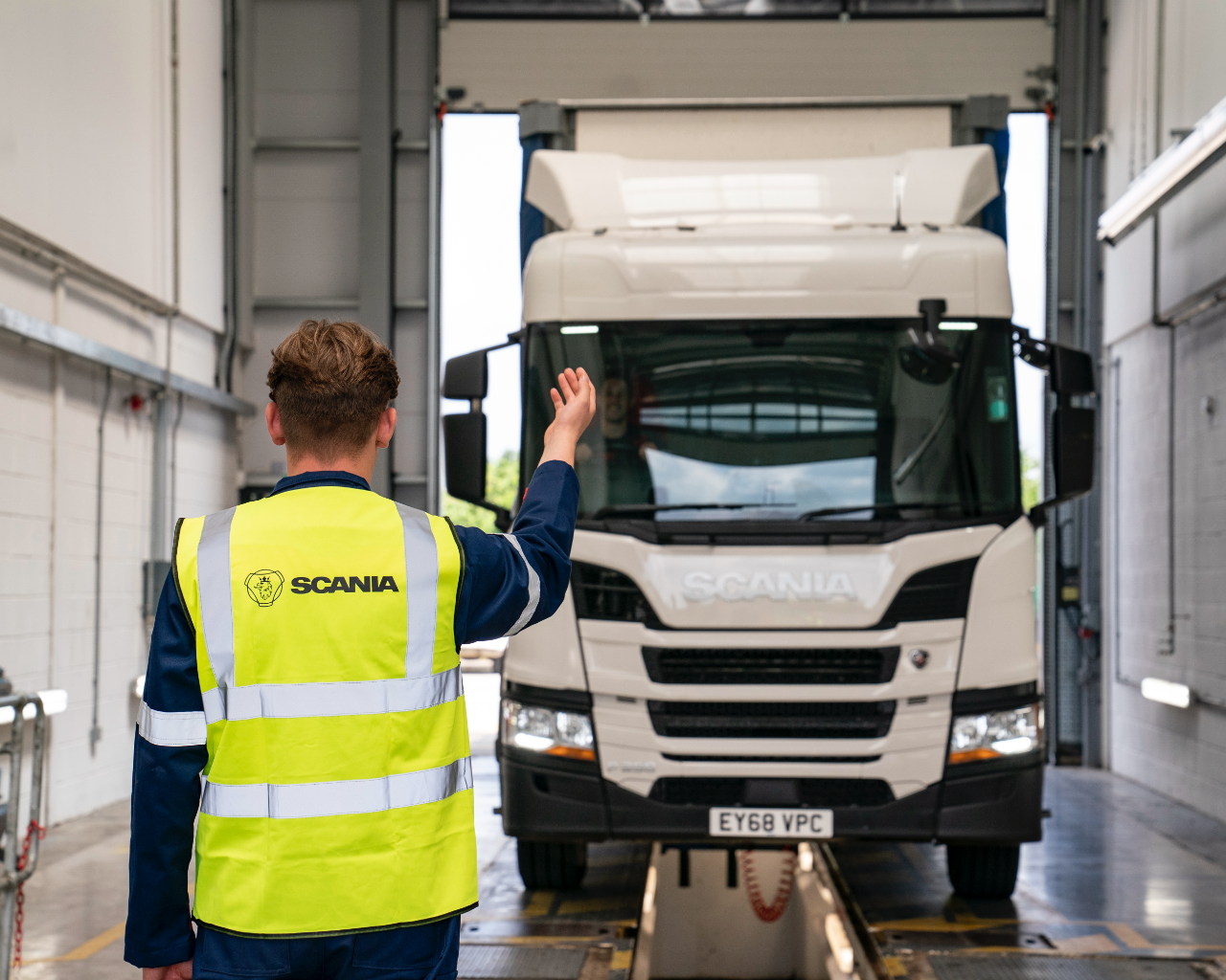 Technician directing Scania into workshop