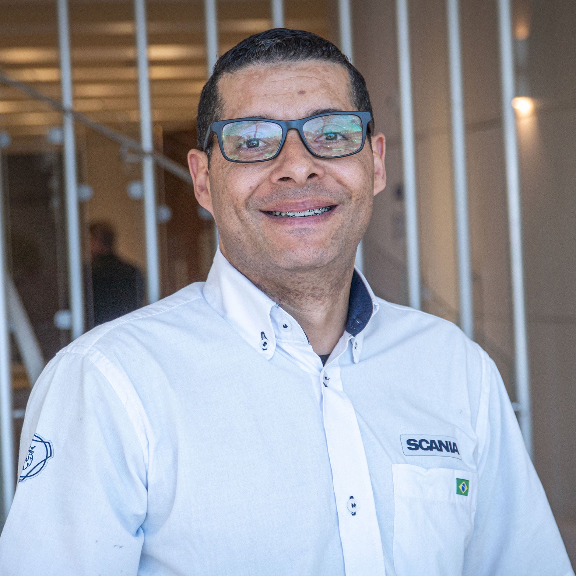 Adriano Ferreira, assembly technician at Scania Brazil, smiling in a white Scania shirt.