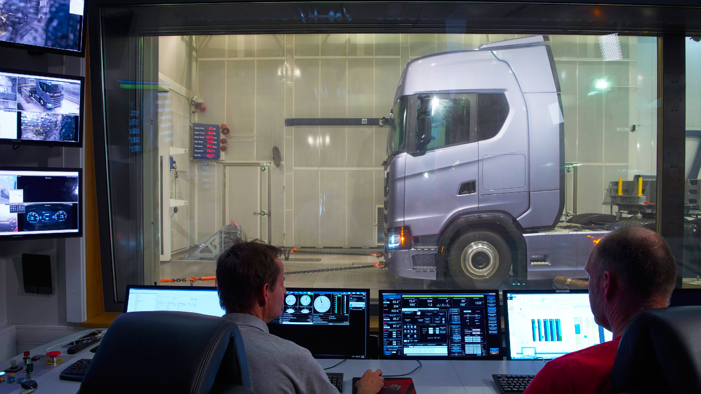 A Scania truck being inspected on by Scania workers A Scania truck being inspected on by Scania workers