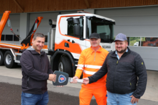 Reto Wagner überreicht den beiden Fahrern Peter Grieder und Joël Schwyzer sym-bolisch den Fahrzeugschlüssel und wünscht gleichzeitig gute und sichere Fahrt mit dem neuen Scania.