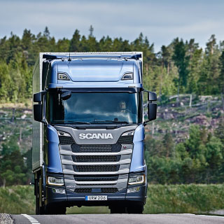 Blå Scania-lastbil kører på landevejen
