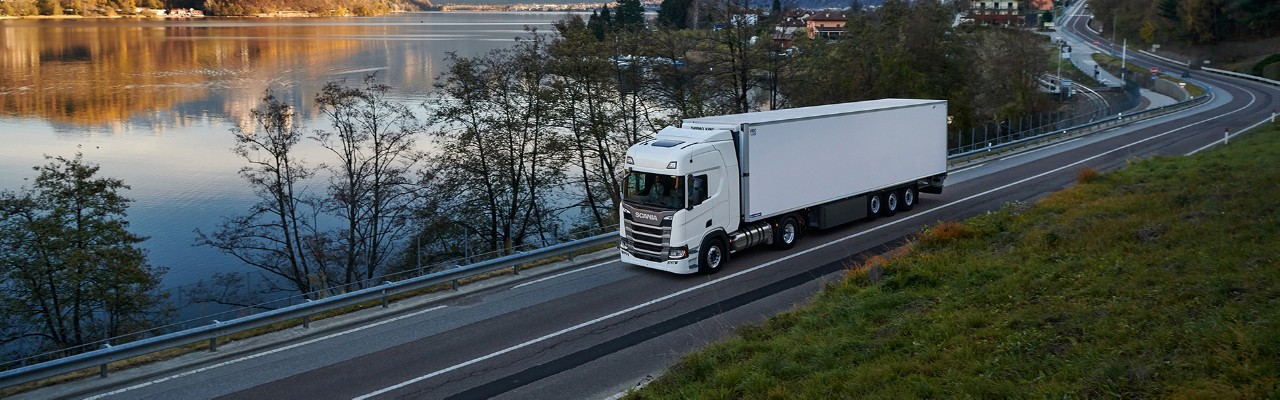 Um cruzeiro branco Scania linha R em uma pequena estrada com a melhor eficiência de combustível