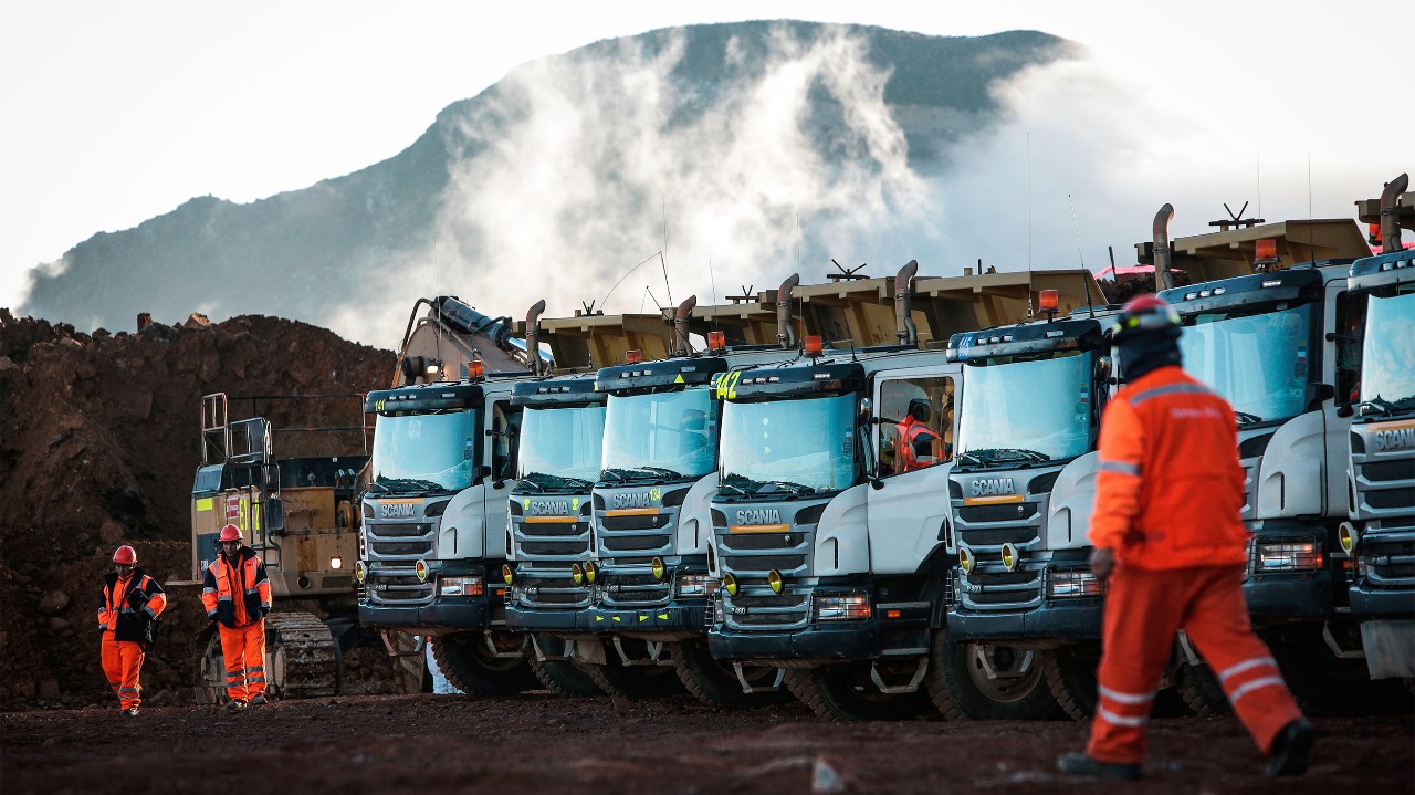 Lidé a nákladní vozidla v těžebním prostředí