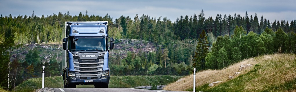 Blå Scania-lastbil kører på landevejen