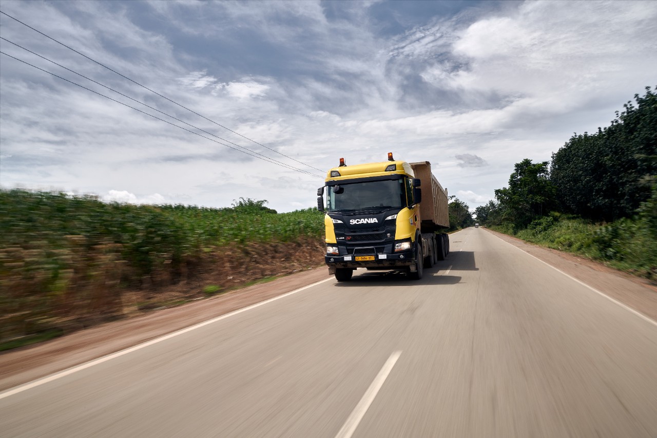 A Scania G460 cruising on a road surrounded by greenery and complimented by a blue sky