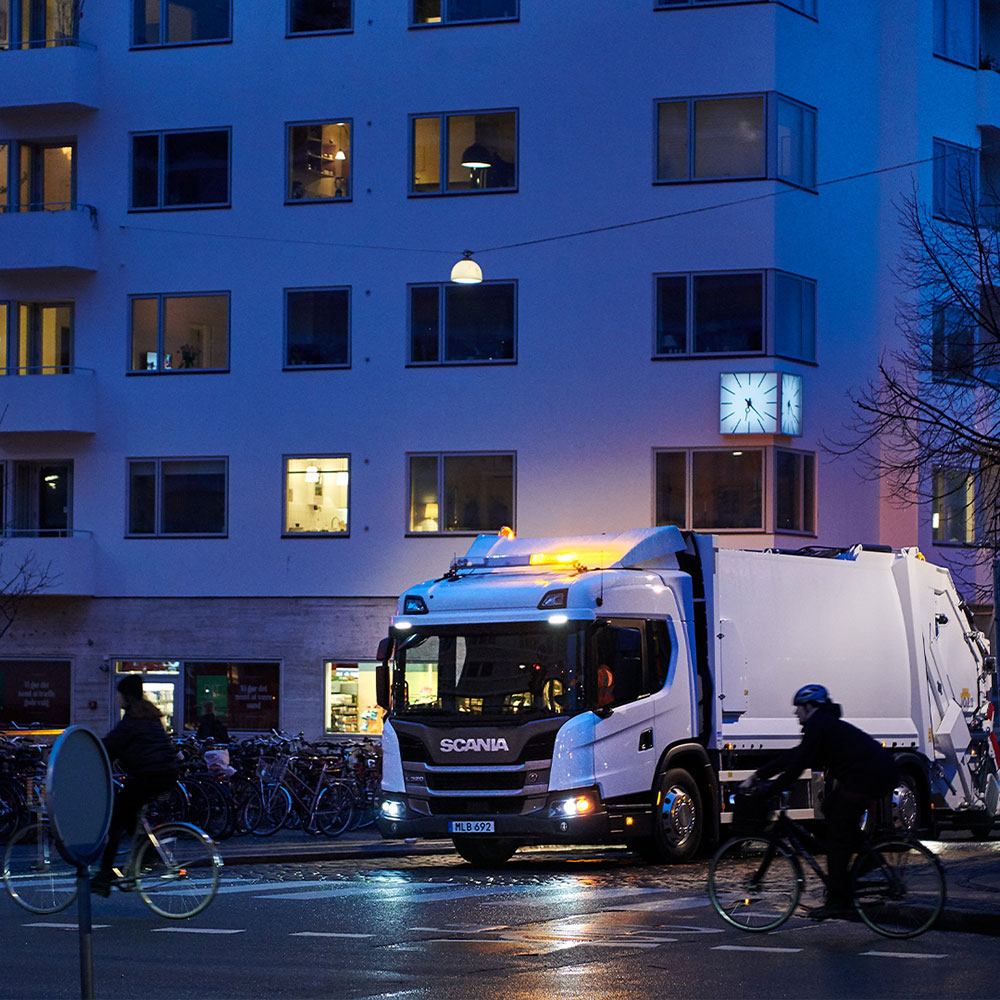 A Scania truck stopping for two cyclists crossing the street
