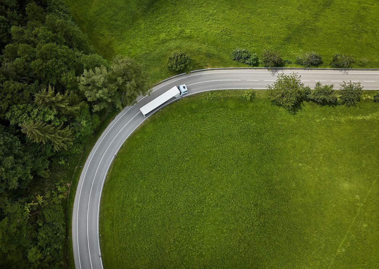 Aerial view of a Scania truck driving along a narrow road surrounded by green fields