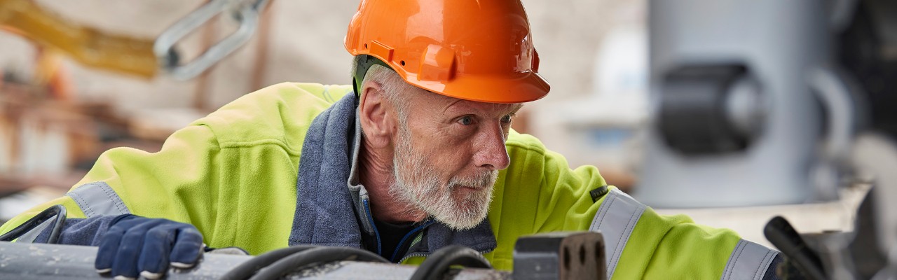 A man with a safety helmet inspecting a Scania vehicle