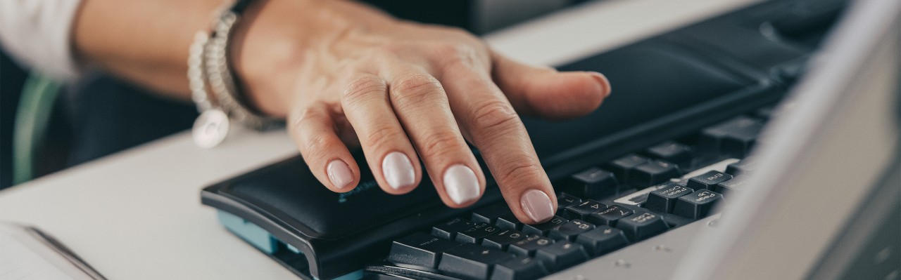  O mână pe tastatura unui computer