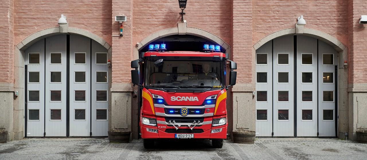 Brandbil med blåljus påväg ut ur garage i brandstation