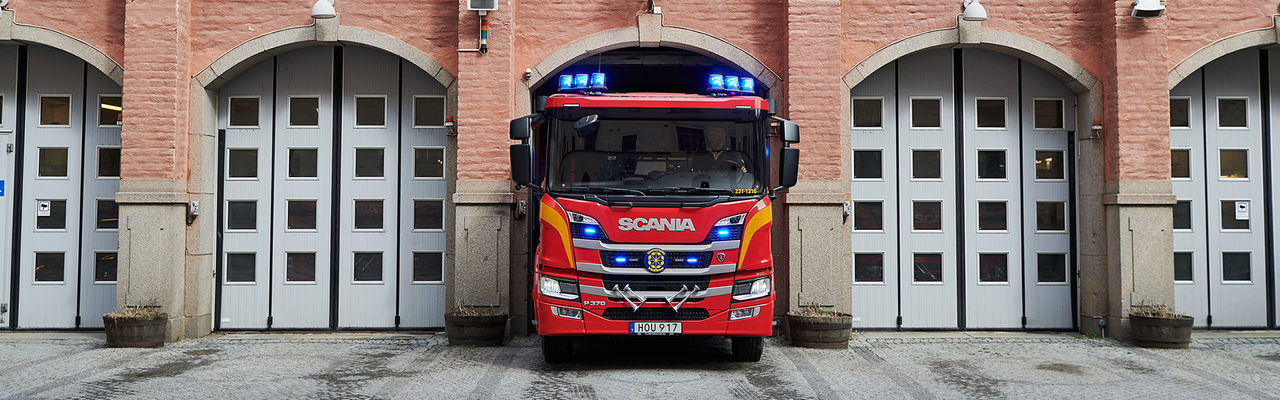 Brandbil med blåljus påväg ut ur garage i brandstation