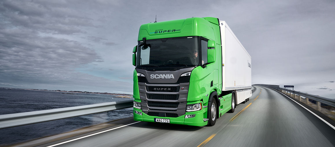 Grön Scania Super på väg över en bro
