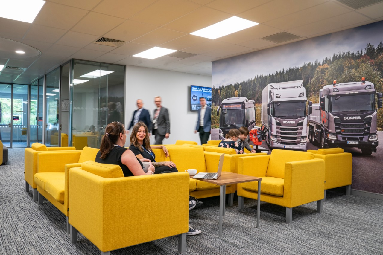 Scania colleauges sat in meeting room on yellow chairs talking