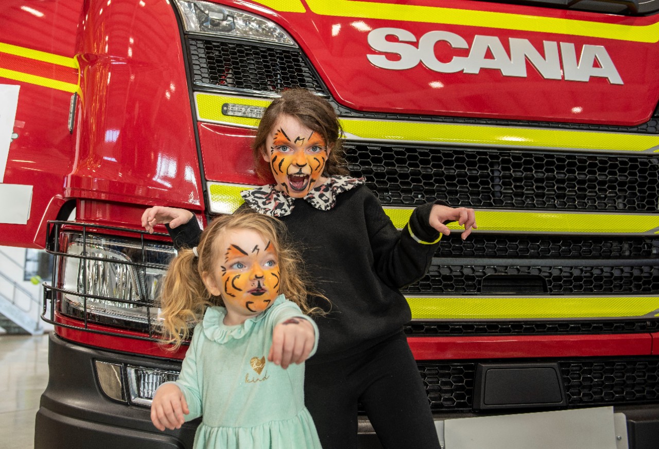 Children with face paint in front of Scania truck