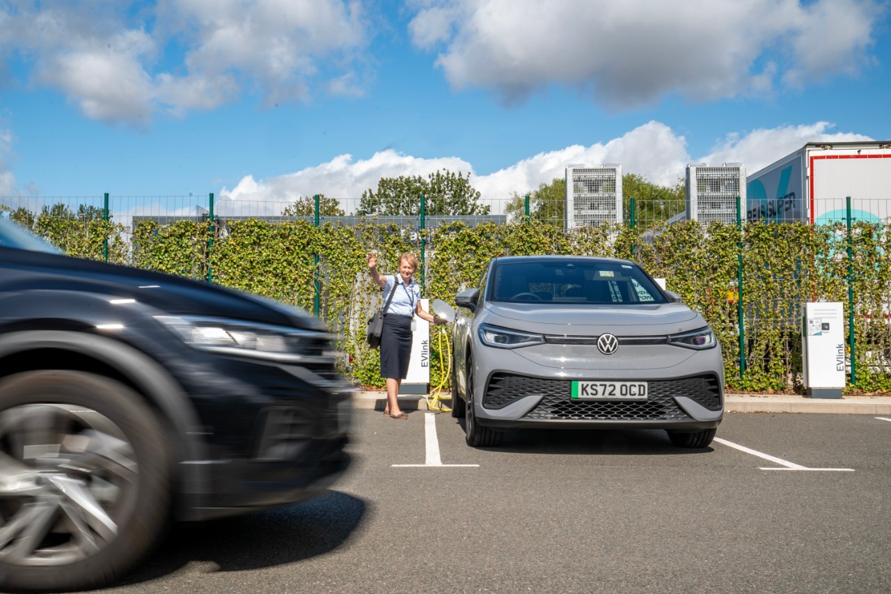 Car driving past women unplugging electric car