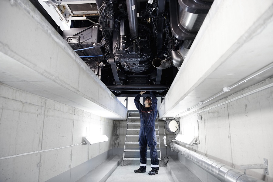 Technician working under a truck in workshop