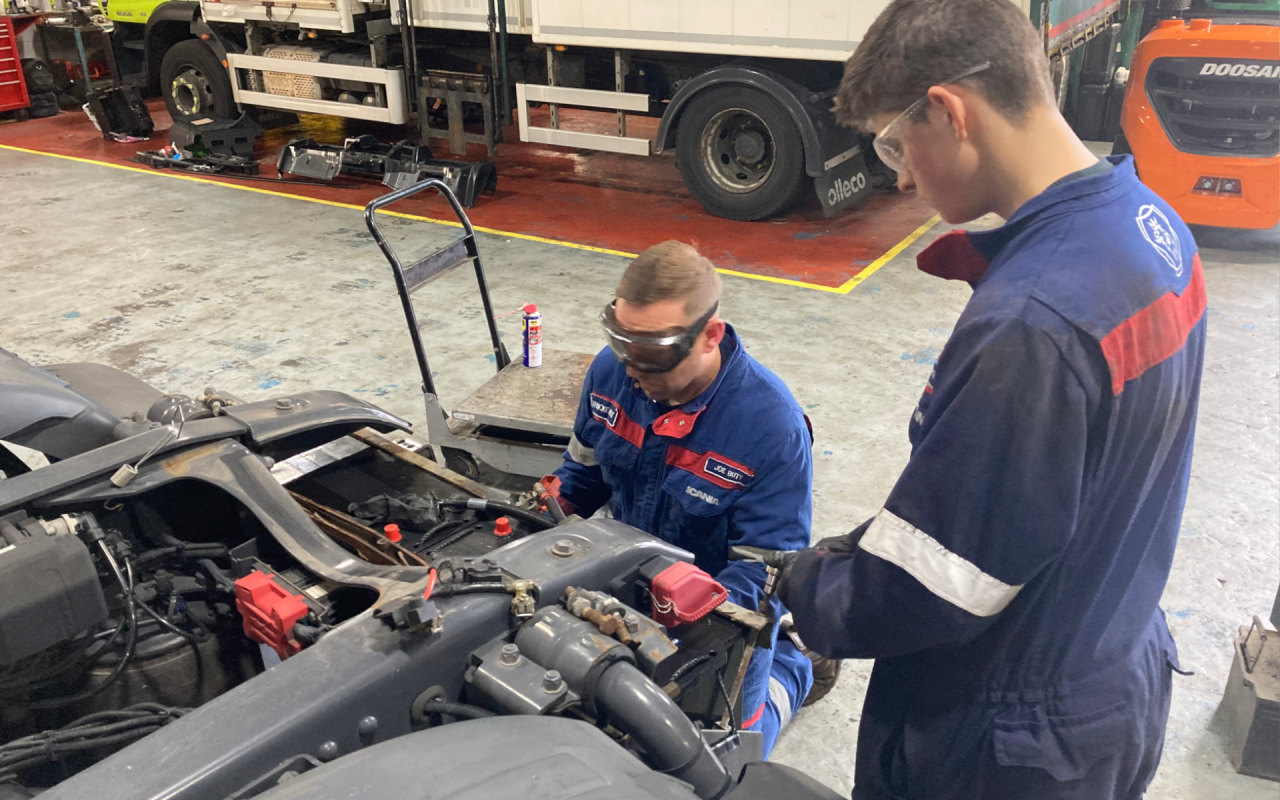 Apprentice and mentor changing truck battery