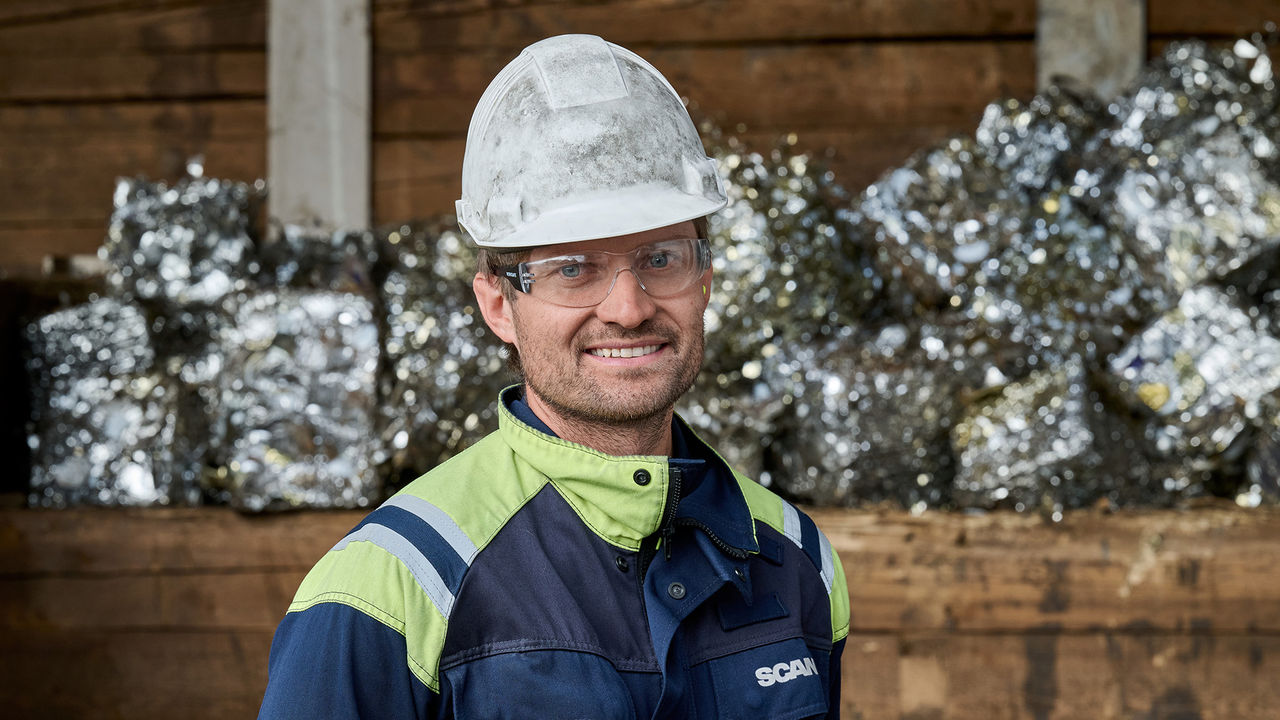 Christopher Armstrong, Process Engineer at Scania's foundry, standing infront of compressed scrap metal ready for melting.
