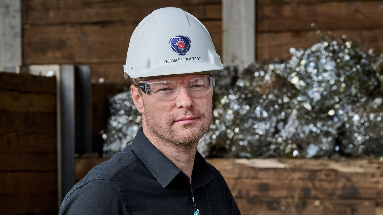 Thomas Lindstedt, Production Manager at Scania, standing infront of compressed scrap metal ready for melting.