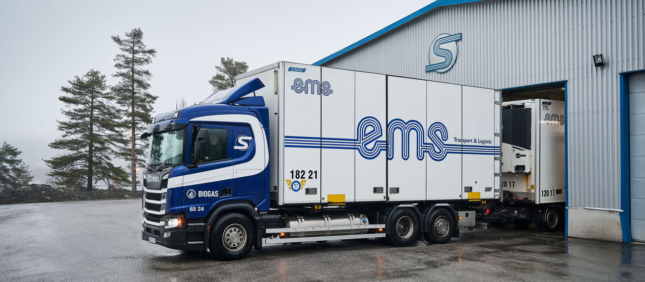 A blue Scania biogas truck parked outside EMS Transport & Logistik's terminal in Örnsköldsvik, Sweden.